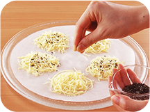 画像：耐熱皿に敷いたクックパークッキングシートにピザ用チーズをのせてごまをふっている