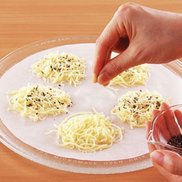 画像：耐熱皿に敷いたクックパークッキングシートにピザ用チーズをのせてごまをふっている
