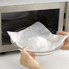 画像：耐熱皿にしいたクックパークッキングシートに塩をのせ電子レンジに入れている